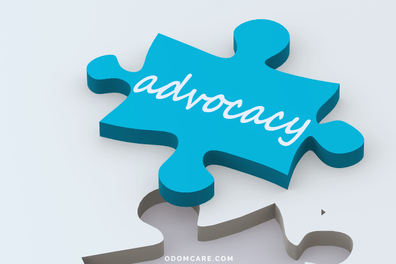 A blue puzzle piece with the word 'advocacy' written in white script is positioned slightly above its corresponding puzzle space. The background is a light gray, creating a clean and modern look. The website 'ODOMCARE.COM' is displayed at the bottom of the image.
