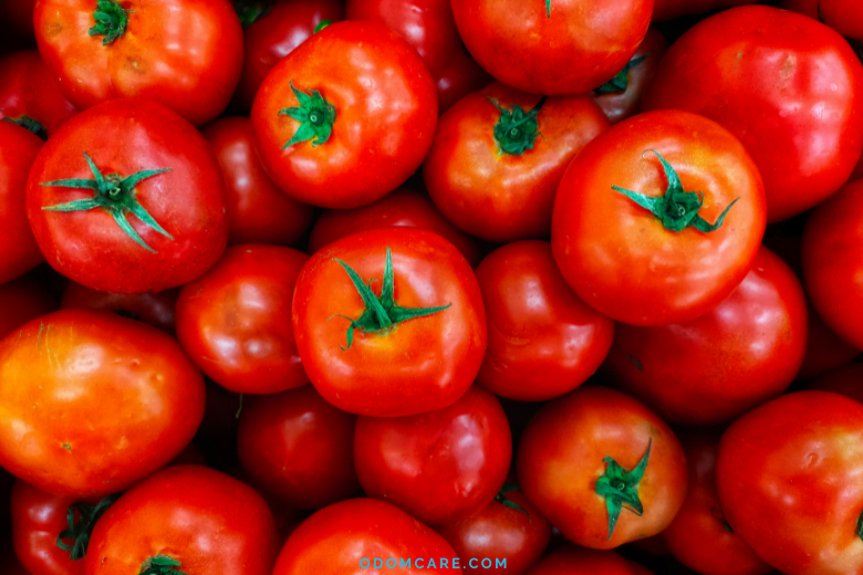 Fresh red tomatoes with green stems.